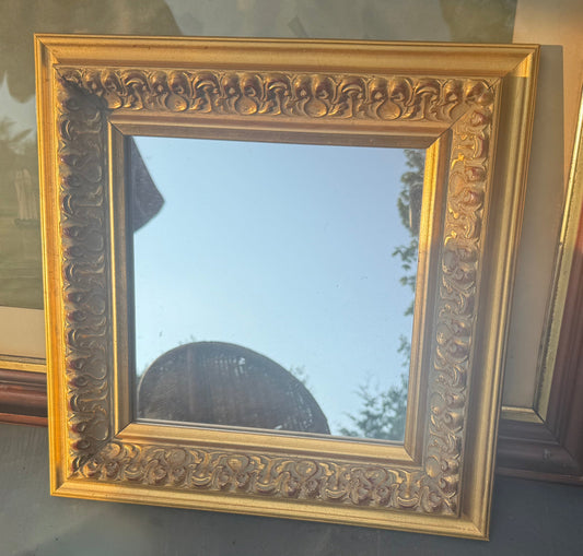 Decorative gold-framed mirror on a table